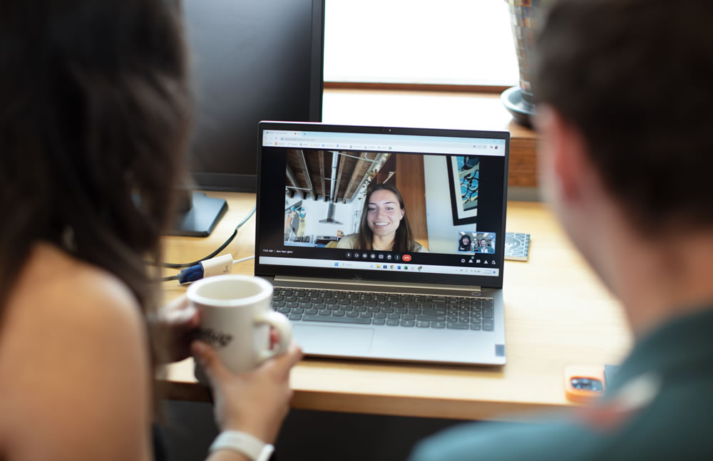 Photo of two employees talking to a woman on a video call
