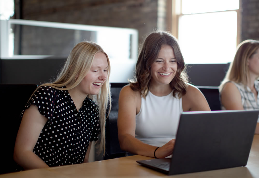 Photo of two women working together around a laptop